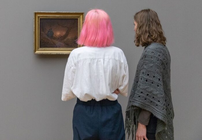 Zwei Besucherinnen, eine mit rosa Haaren, betrachten ein das Bild Mondsüchtig von Caspar David Friedrich
