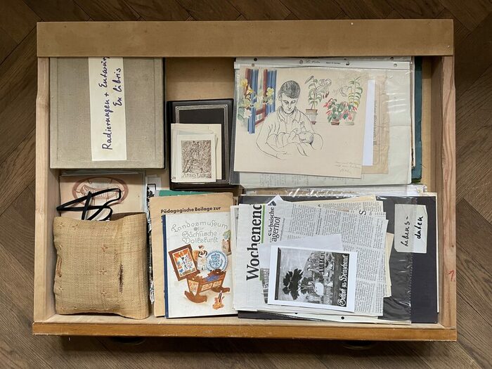 Eine geöffnete Schublade. darin Zeitungen, Zeichnungen, Bilder und Dokumente