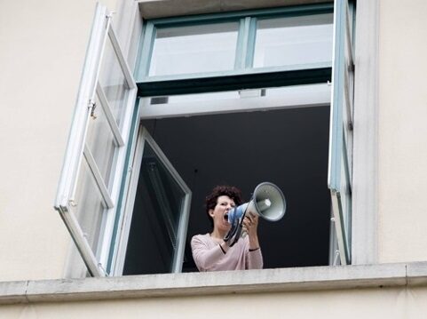Eine Frau am Fenster schreit durch ein Megafon