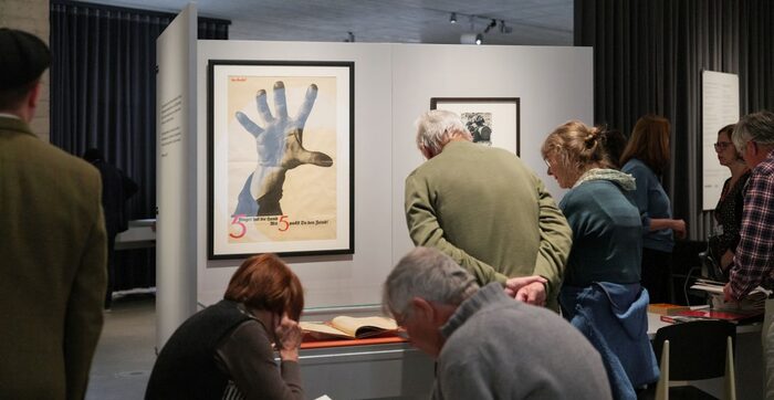 Menschen betrachten in der Ausstellung Objekte in Vitrinen