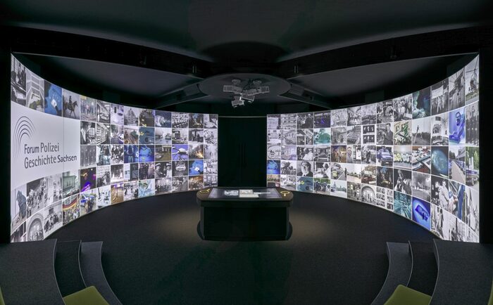 Eine große, wandbreite Projektion mit Bildern von Ausstellungsstücken