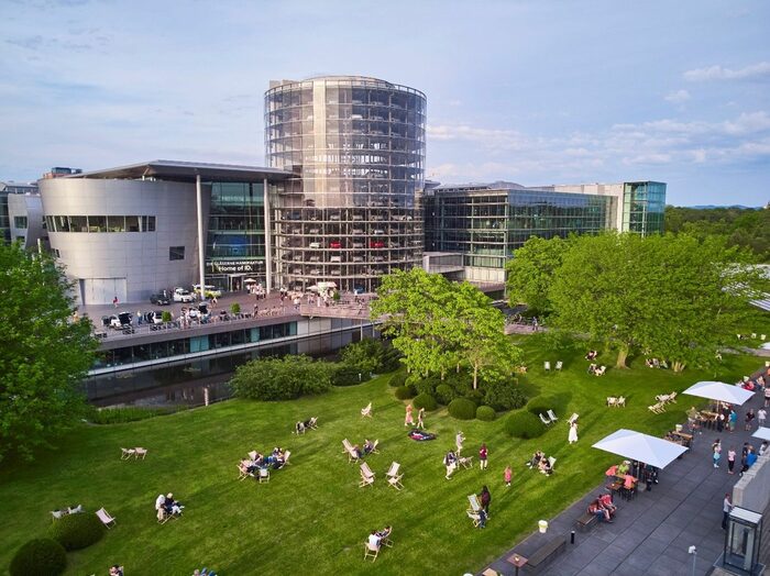 Außenblick auf die Gläserne Manufaktur mit vielen Menschen vom Großen Garten aus gesehen. Fertigungsgebäudes